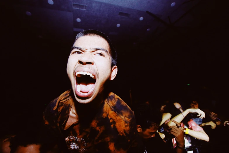 a man standing in front of a crowd with his mouth open, an album cover, unsplash, happening, asian man, goblins partying at a rave, holga, in a nightclub