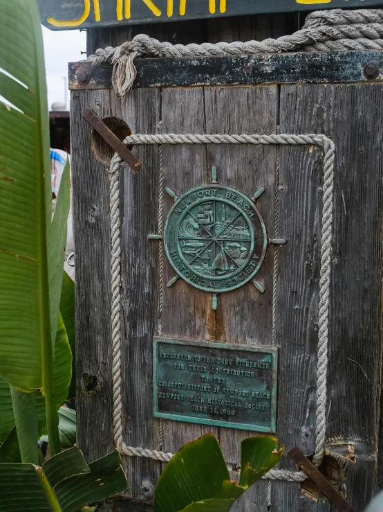 a close up of a sign on a wooden pole, medal, gilligan's island, door, old pirate ship