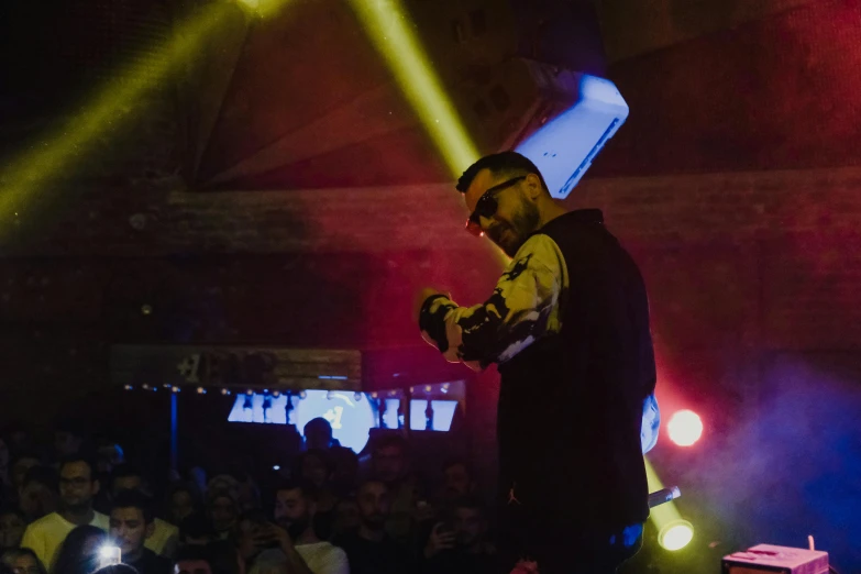 a man standing on top of a stage in front of a crowd, underground party, profile image, cocky smirk, bad bunny