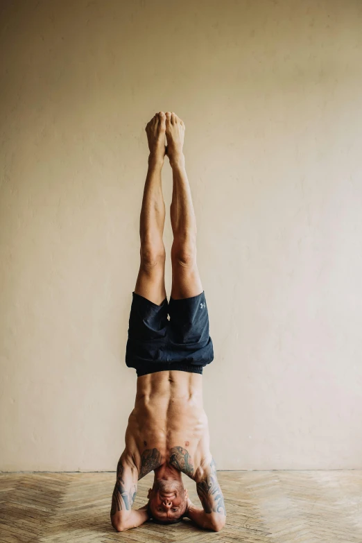 a man doing a handstand in a room, trending on unsplash, arabesque, head torso legs feet, with a spine crown, portrait of tall, yoga