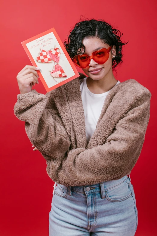 a woman holding a red card in front of her face, an album cover, featured on reddit, pop art, ( bear wearing sunglasses, cozy warm tint, cupid, official store photo