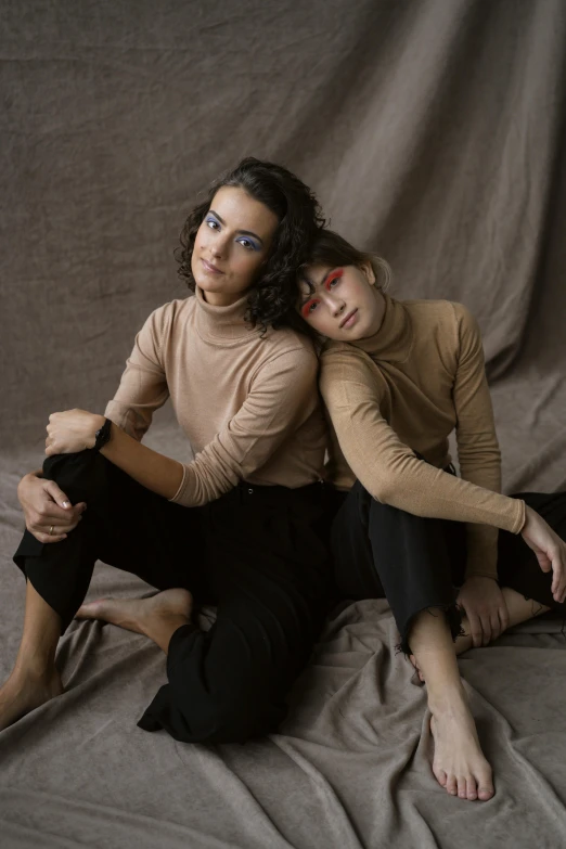 a couple of women sitting on top of a bed, a portrait, trending on unsplash, antipodeans, wearing turtleneck, sitting on a mocha-colored table, shot in the photo studio, album cover