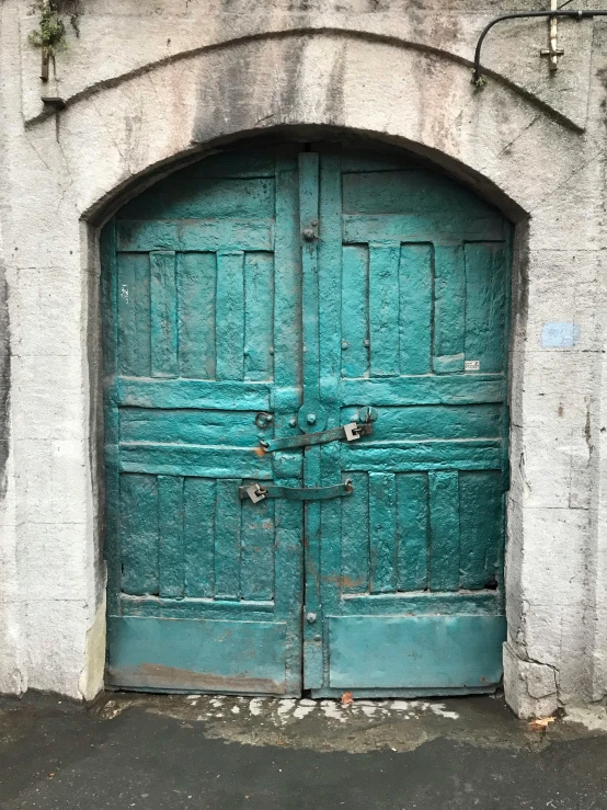 a couple of green doors sitting on the side of a building, an album cover, arte povera, street of teal stone, 1 8 0 0's, rustic yet enormous scp (secure, tallinn
