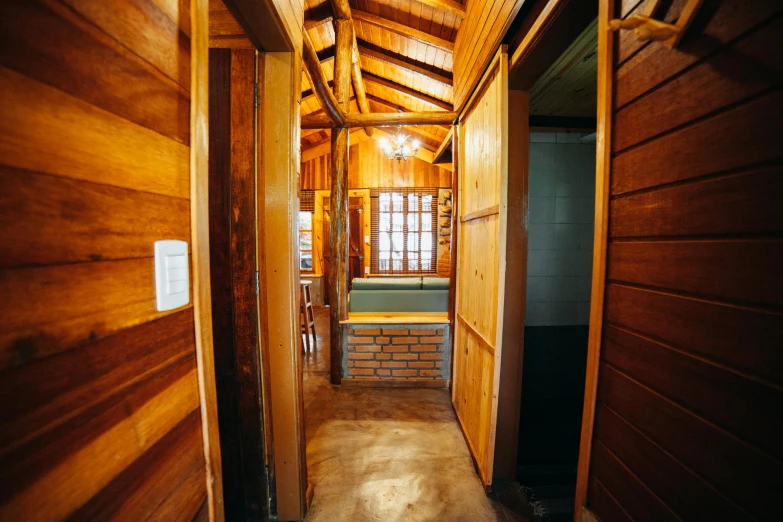 a hallway leading to a room with wooden walls, by Jessie Algie, unsplash, mingei, colombian, toilet, several cottages, slide show