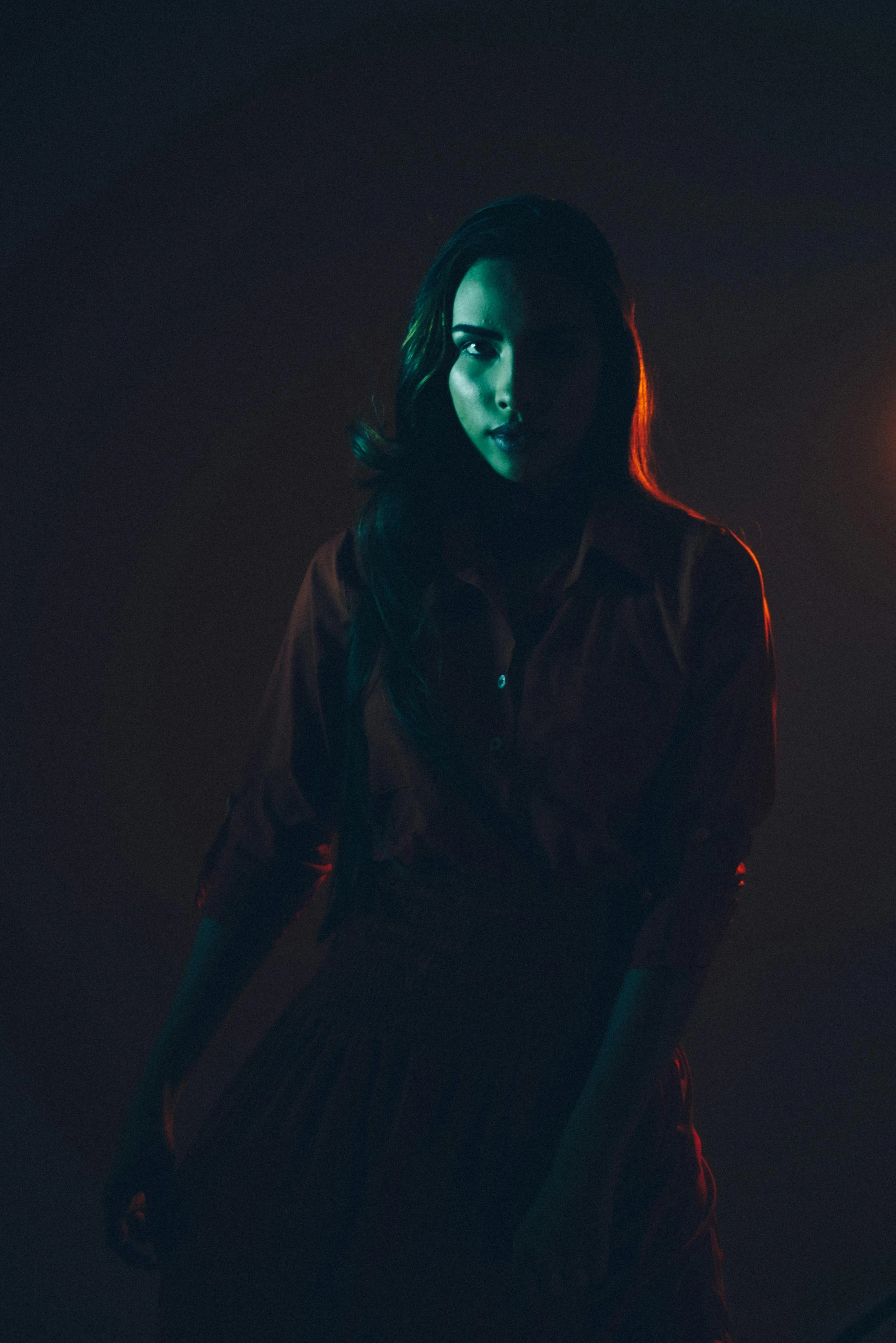 a woman standing in front of a street light, a portrait, pexels contest winner, conceptual art, blood; dark cinematic lighting, in a dark studio room, with haunted eyes and dark hair, promotional image