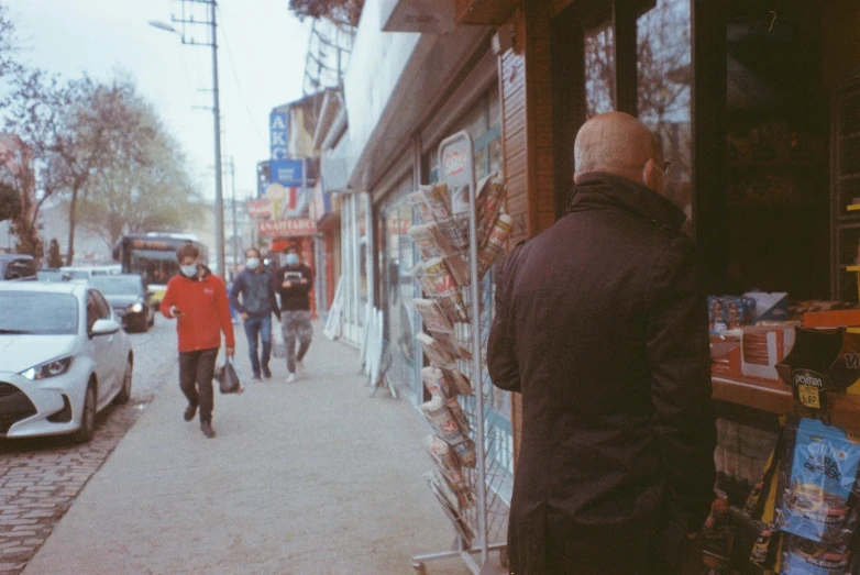 a group of people walking down a sidewalk next to a store, a picture, pexels contest winner, a man wearing a black jacket, lo fi, tehran, walking through a suburb