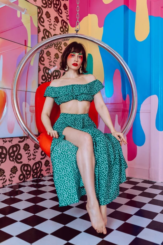 a woman sitting on top of a chair in a room, an album cover, by Julia Pishtar, trending on pexels, maximalism, teal skirt, with bangs, pinup body, patterned clothing