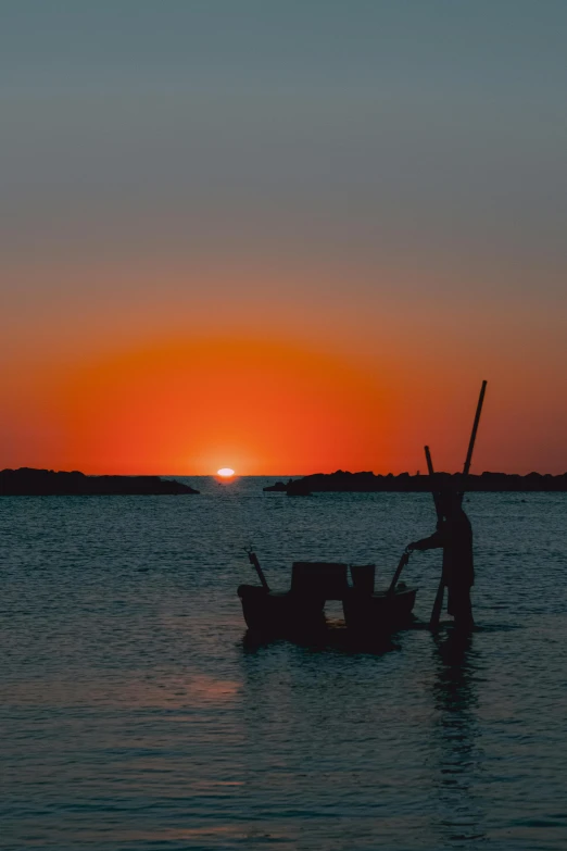 a man that is standing in the water with a boat, pexels contest winner, sunsetting color, fishing village, over the horizon, movie photo