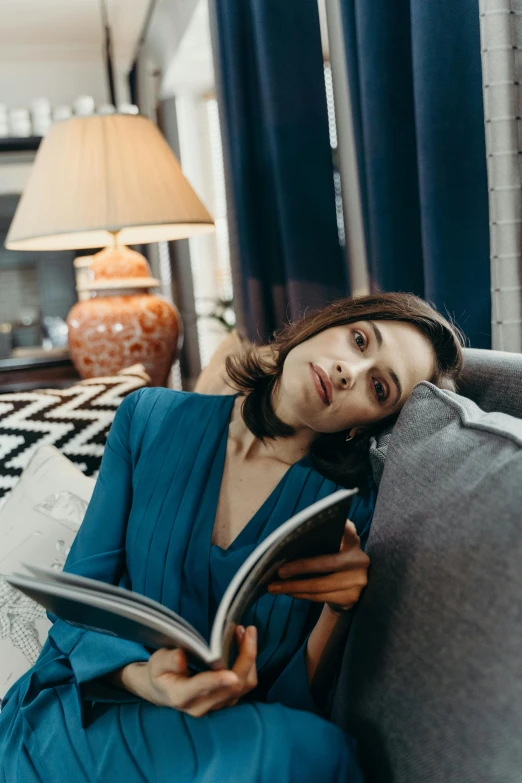 a woman sitting on a couch reading a book, happening, looking exhausted, woman's face looking off camera, 2019 trending photo, portrait photo