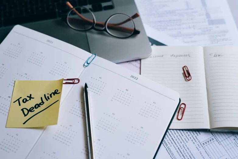 a notepad sitting on top of a desk next to a laptop, trending on pexels, female calendar, black and yellow and red scheme, thumbnail, various items