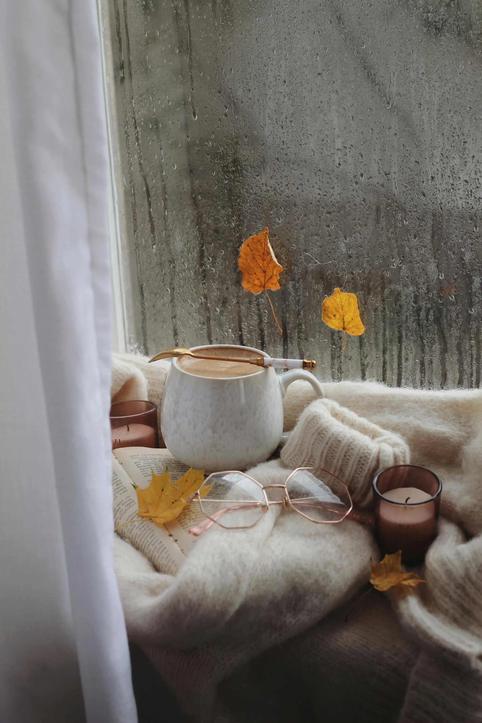 a cup of coffee sitting on top of a window sill, a still life, inspired by Elsa Bleda, trending on pexels, leafs falling, square rimmed glasses, ivory and copper, foggy room