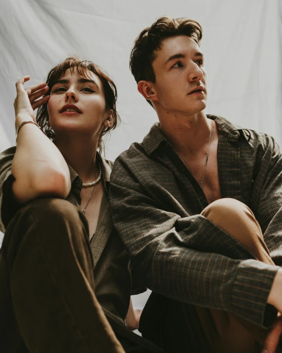 a man and a woman sitting next to each other, an album cover, trending on pexels, beautiful androgynous girl, casual modern clothing, lily frank, asher duran