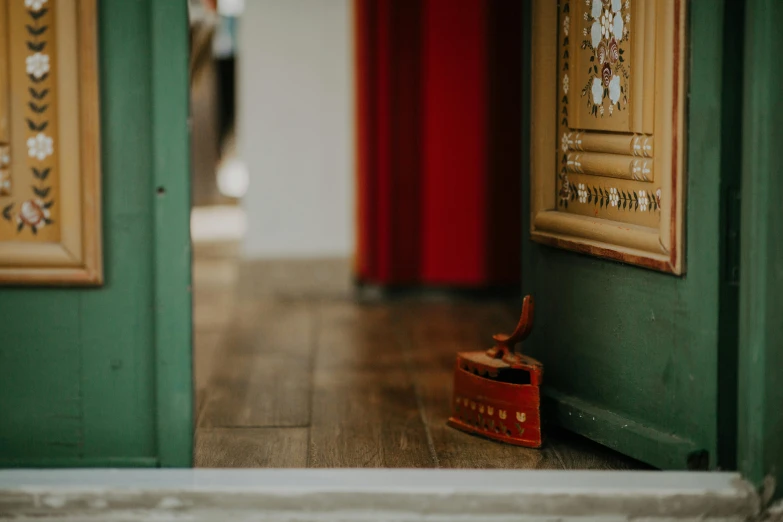 a pair of shoes sitting on top of a wooden floor, by Emma Andijewska, pexels contest winner, cloisonnism, doorway, red green, background image, interior of a victorian house