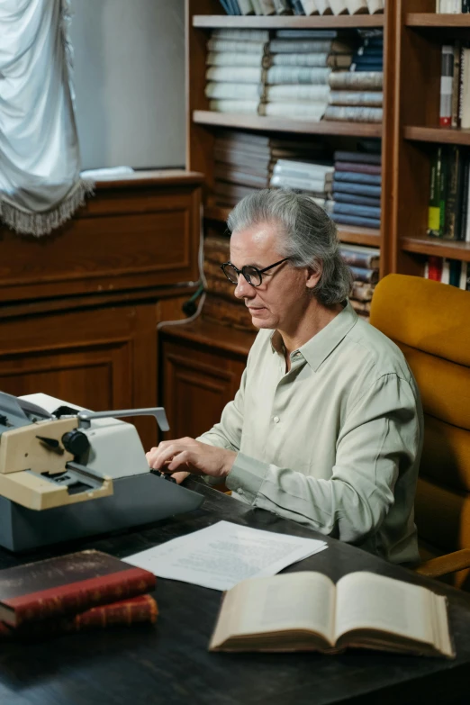 a man sitting at a desk typing on a typewriter, jimmy page, man with glasses, investigation, ignant