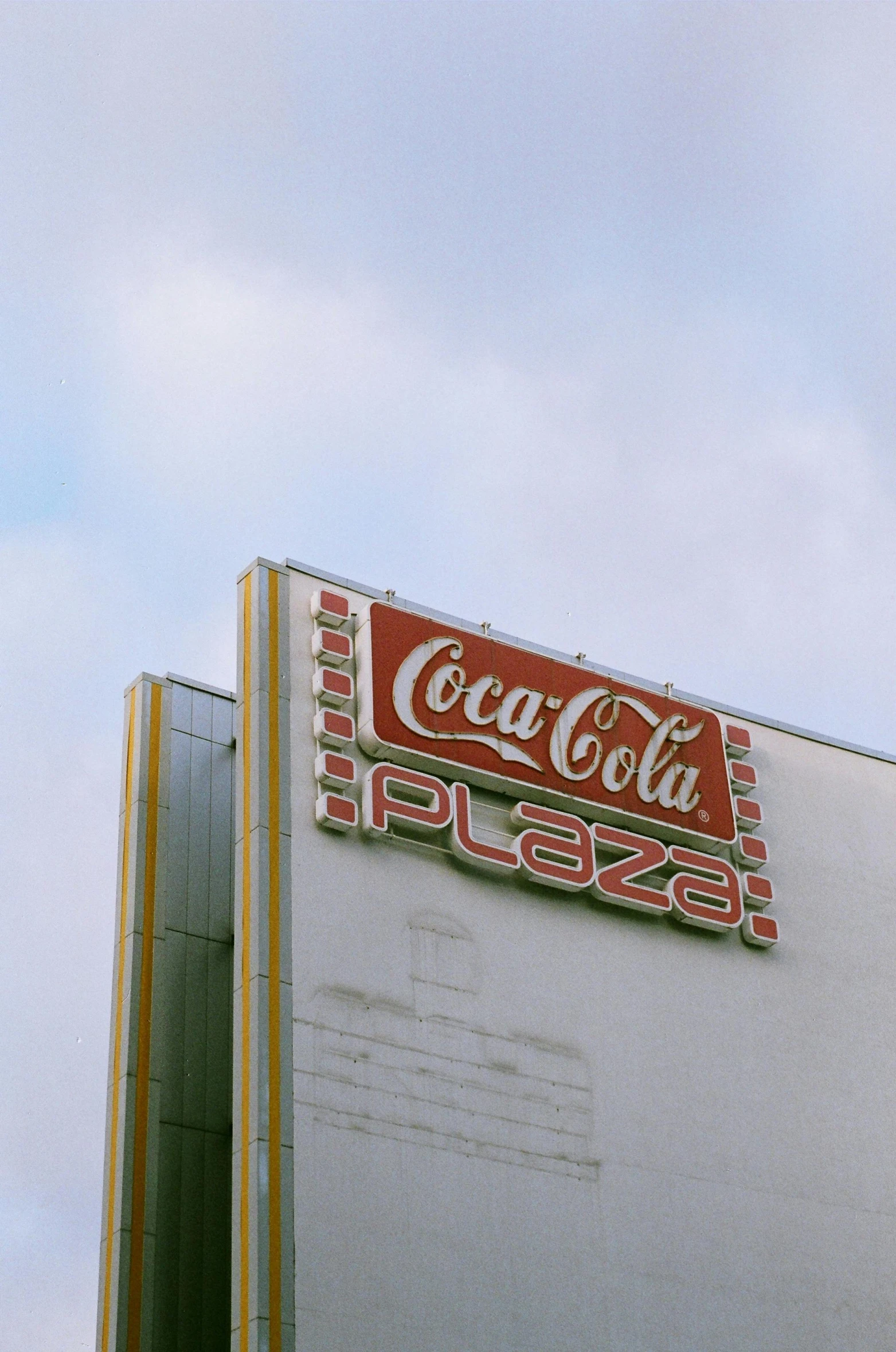 a coca cola sign on the side of a building, a colorized photo, inspired by Elsa Bleda, trending on unsplash, pizza skyscrapers, ( ( theatrical ) ), plaza, hollywood promotional image