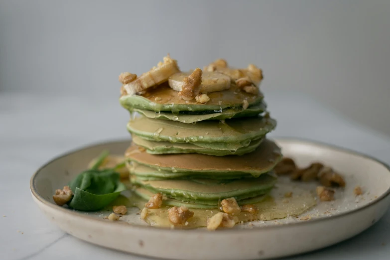 a stack of pancakes sitting on top of a white plate, by Emma Andijewska, greens, raw file, beaten, banana