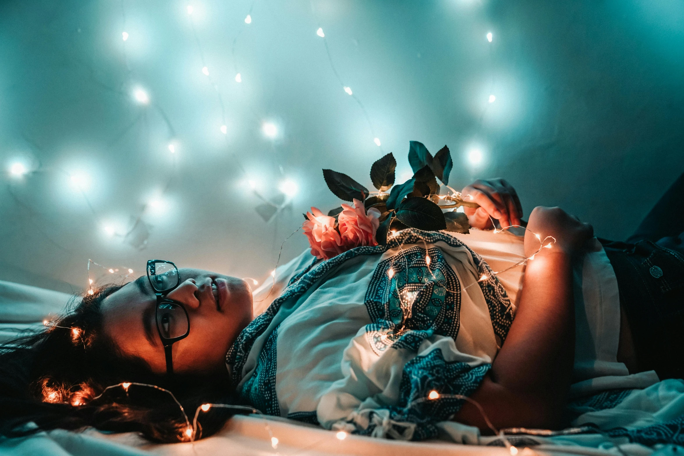 a woman laying on top of a bed covered in lights, inspired by Elsa Bleda, trending on pexels, avatar image, covered in plants, awkward, half image