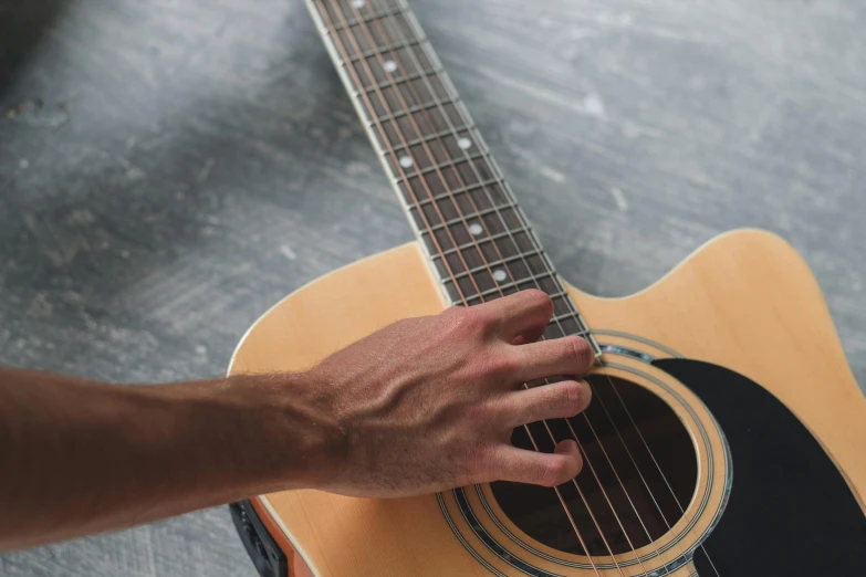 a close up of a person holding a guitar, on a gray background, multiple stories, hand on table, thumbnail