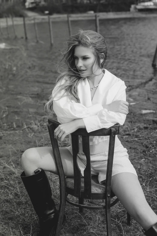 a black and white photo of a woman sitting in a chair, a black and white photo, trending on pexels, white outfit, high boots, in nature, handsome girl