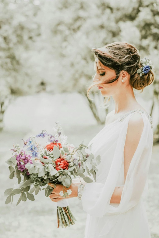 a woman in a white dress holding a bouquet of flowers, a colorized photo, pexels contest winner, soft grey and blue natural light, playful updo, rustic setting, red and blue color theme