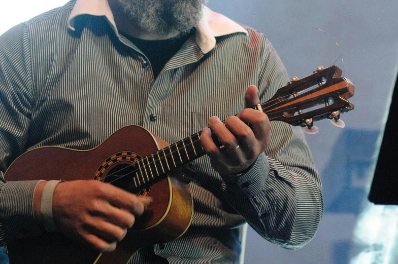 a man with a beard playing a guitar, photo from a spectator, ukulele, promo image, from the elbow