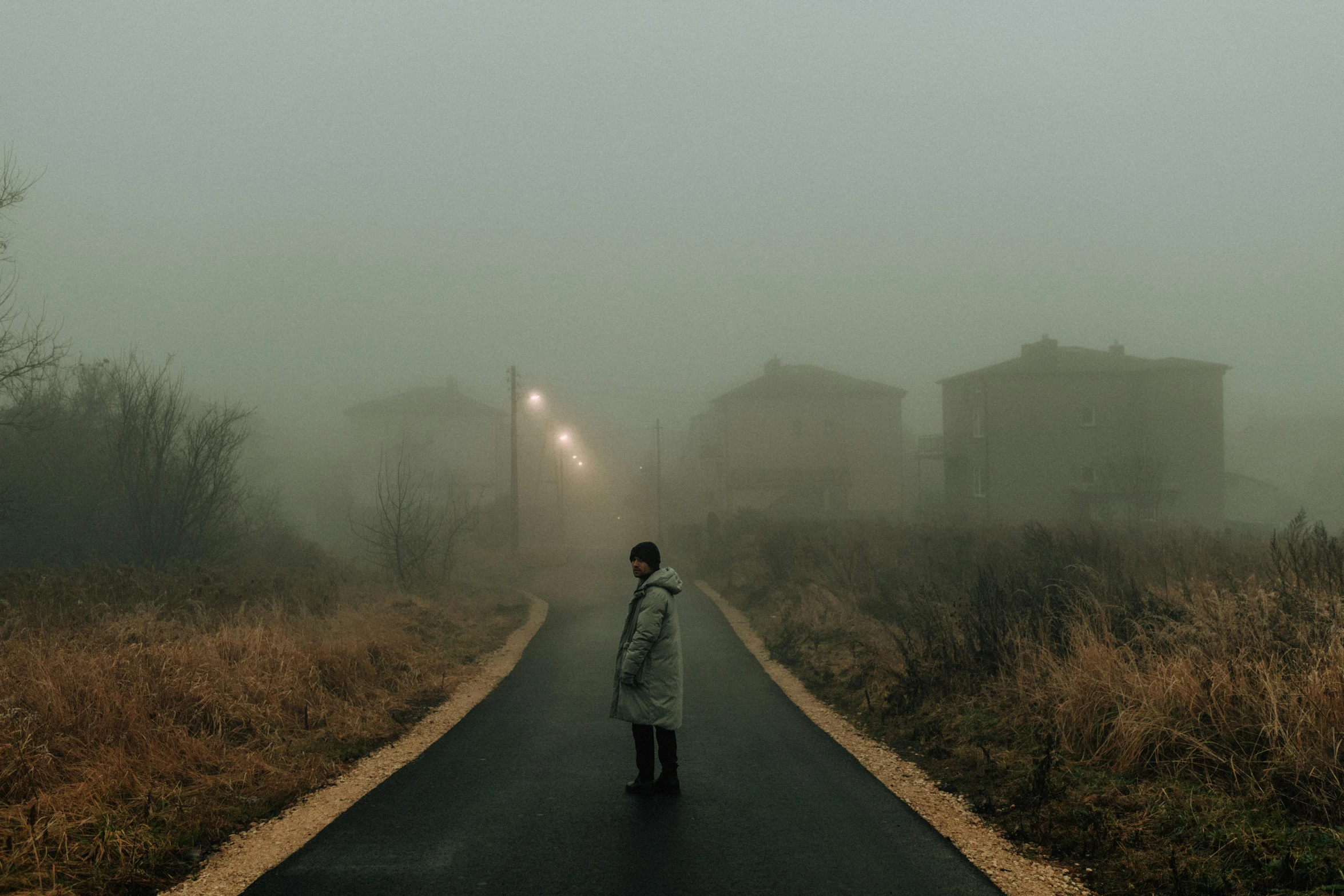 a person walking down a road on a foggy day, an album cover, inspired by Elsa Bleda, pexels contest winner, magical realism, italian horror, abandoned town, panoramic view of girl, teenage boy