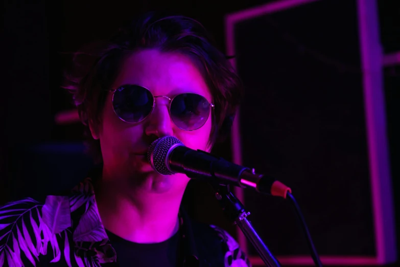 a woman in sunglasses singing into a microphone, an album cover, by Winona Nelson, pexels, timothee chalamet, stoner rock concert, julian ope, low iso