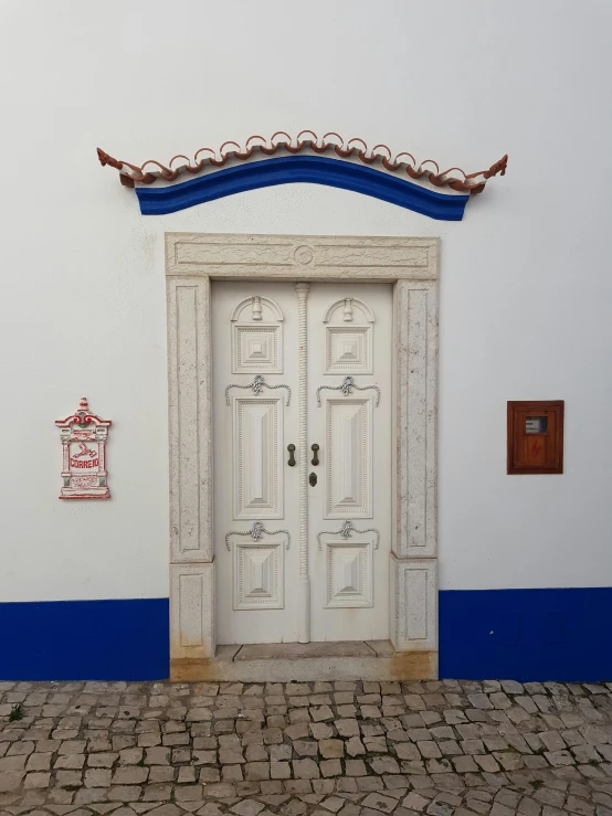 a white door sitting on the side of a building, a photo, by Bernardo Daddi, cloisonnism, farol da barra, square, average, set photo