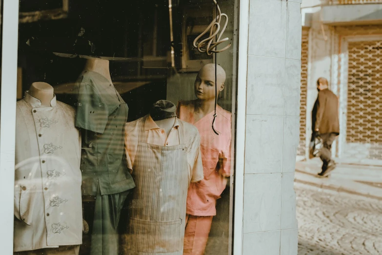 a couple of mannequins that are in a window, pexels contest winner, vintage clothing, surgical gown and scrubs on, sunfaded, a person standing in front of a