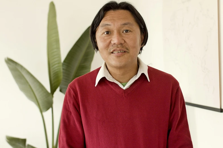 a man in a red sweater standing in front of a plant, shin hanga, hoang lap, portrait image, architect, in 2 0 1 2