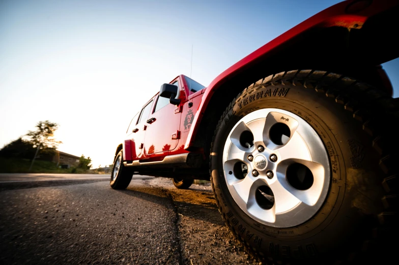 a red jeep parked on the side of a road, pexels contest winner, detailed alloy wheels, golden hour closeup photo, super high resolution, made with unreal engine