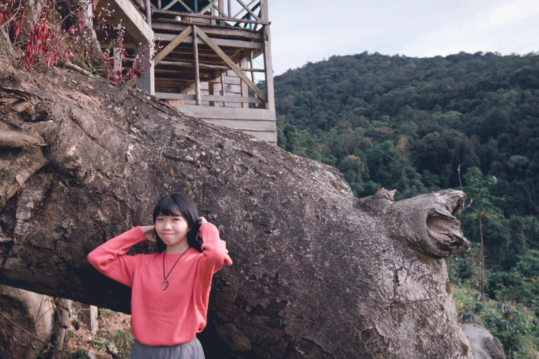 a woman standing in front of a large tree, inspired by Ma Yuanyu, unsplash, sumatraism, tree house, standing on a cliffside, low quality photo, full frame image