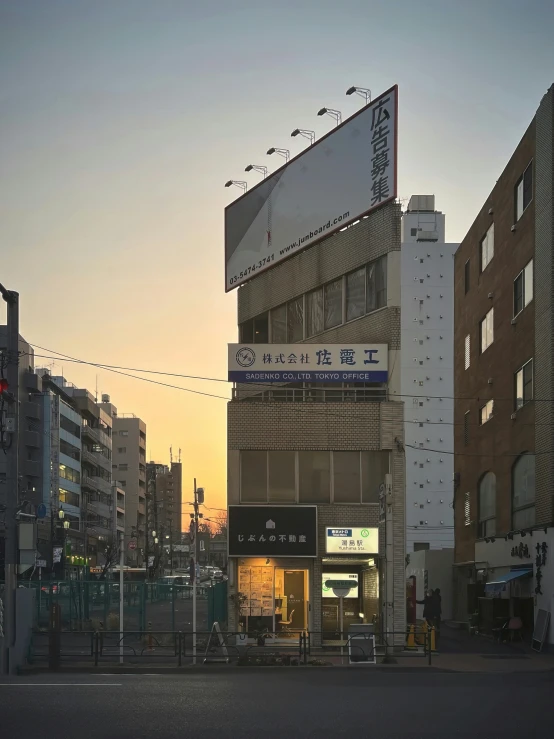 a tall building sitting on the side of a road, a photo, inspired by Kanō Naizen, shin hanga, ((sunset)), shops, eichiro oda, photographic hyperrealism