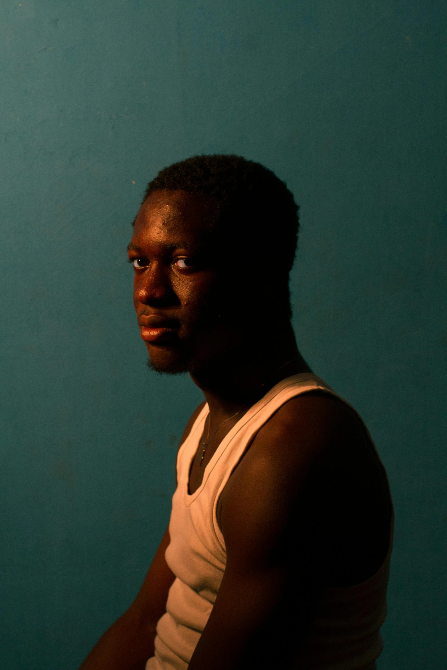 a man sitting in front of a laptop computer, an album cover, photorealism, very dark brown skin!, ((portrait)), photographed for reuters, 2 4 - year - old man