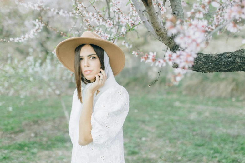 a woman in a hat talking on a cell phone, inspired by Oleg Oprisco, pexels contest winner, aestheticism, almond blossom, dressed in a white t shirt, alena aenami and lilia alvarado, wearing a simple robe