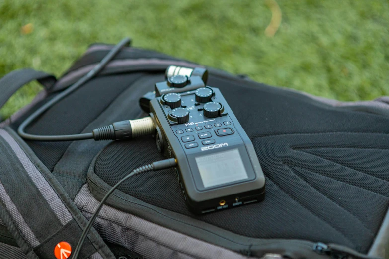 a remote control sitting on top of a backpack, on the field, sitting in front of a microphone, field notes, gorecore