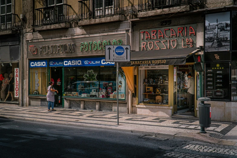 a couple of people that are standing in the street, a photo, by Tobias Stimmer, pexels contest winner, hyperrealism, the city of lisbon, lots of signs and shops, parce sepulto, convenience store