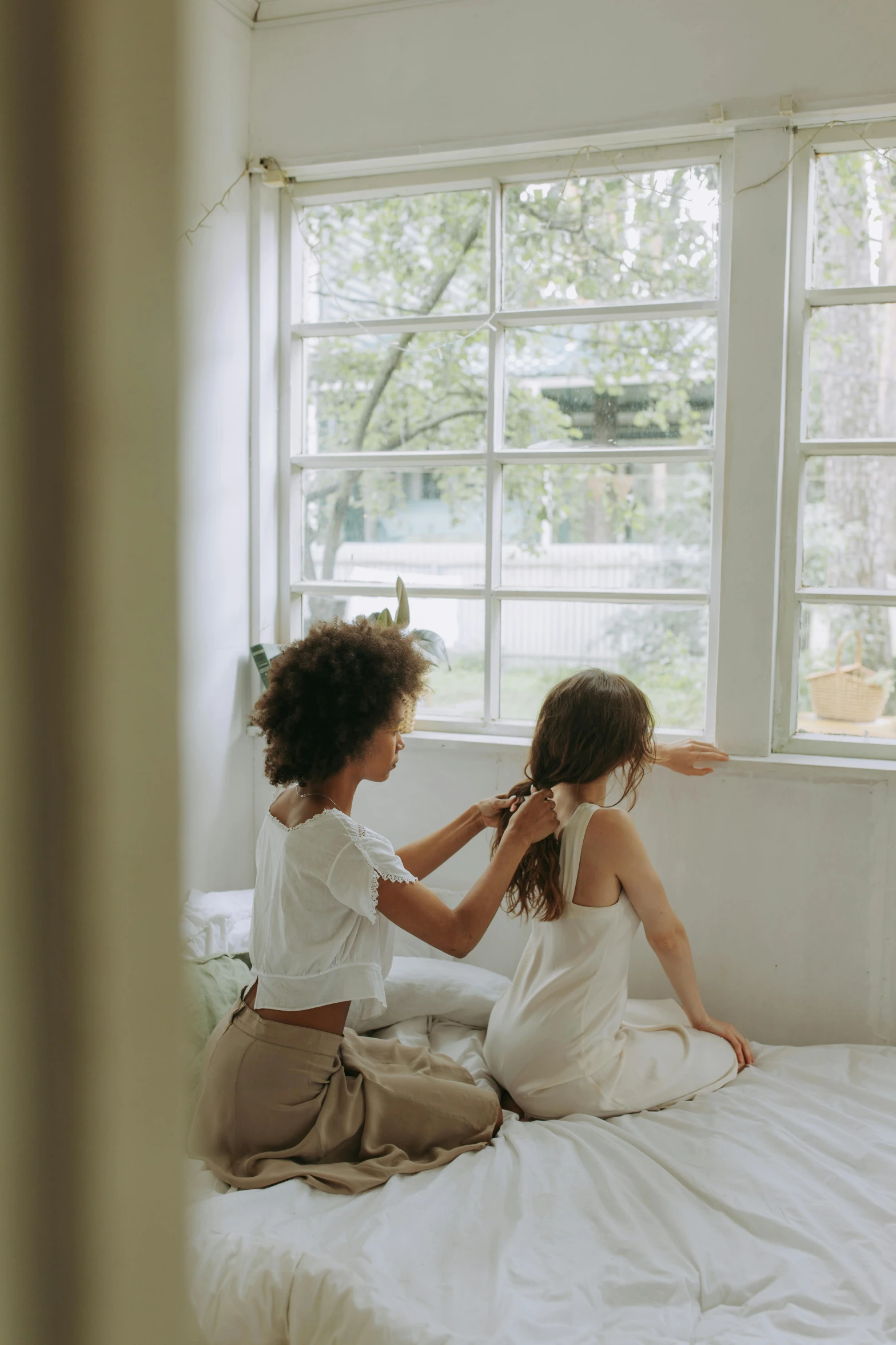 a couple of women sitting on top of a bed, next to a window, kids playing, best practice, hair