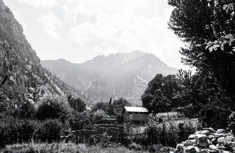 a black and white photo of a mountain range, by Muggur, small cottage in the foreground, amidst of nature fully covered, nature photo