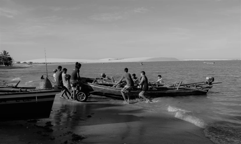 a group of men standing on top of a beach next to boats, a black and white photo, by Peter Churcher, hurufiyya, madagascar, street photo, skiff, taken at golden hour