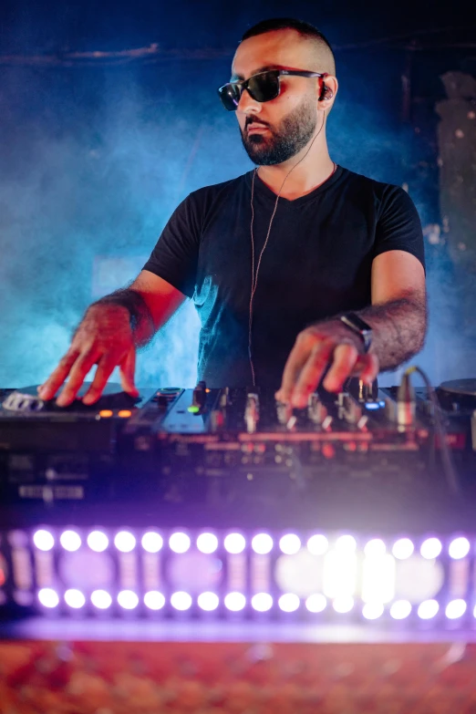 a man that is standing in front of a dj, inspired by Nadim Karam, pexels contest winner, renaissance, stage at a club, with a beard and a black shirt, concentration, press shot