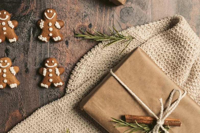 a gift wrapped in brown paper sitting on top of a wooden table, by Emma Andijewska, pexels contest winner, folk art, gingerbread people, background image, flatlay, high-resolution