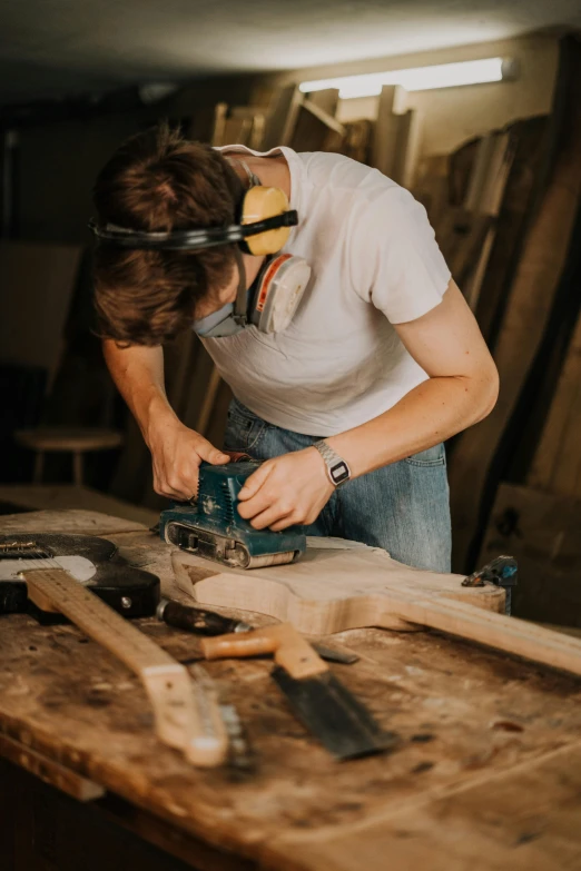 a man using a circular saw to cut a piece of wood, an album cover, trending on pexels, arbeitsrat für kunst, australian, wooden headphones, profile picture, artist wearing overalls