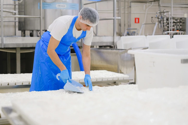 a man in a blue apron working in a factory, by Lisa Milroy, pexels, process art, plenty mozzarella, in australia, sea foam, avatar image