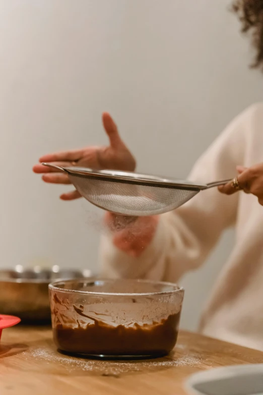 a woman holding a spoon over a bowl of food, glinting particles of ice, improvisational, brown, trending photo