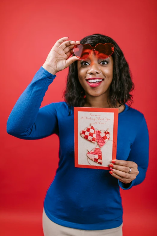 a woman holding a valentine card in front of her face, a photo, by Lena Alexander, shutterstock contest winner, paper cutouts of plain colors, augusta savage, shot in the photo studio, red and blue garments