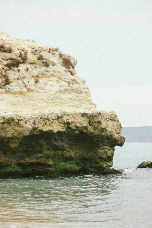 a large rock in the middle of a body of water, by Yerkaland, jerez, on a cliff, lomography photo, video footage