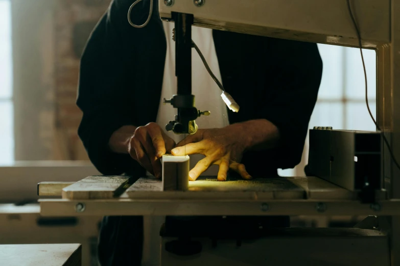 a close up of a person working on a machine, pexels contest winner, arts and crafts movement, clamp shell lighting, rectangle, chopping hands, dezeen showroom