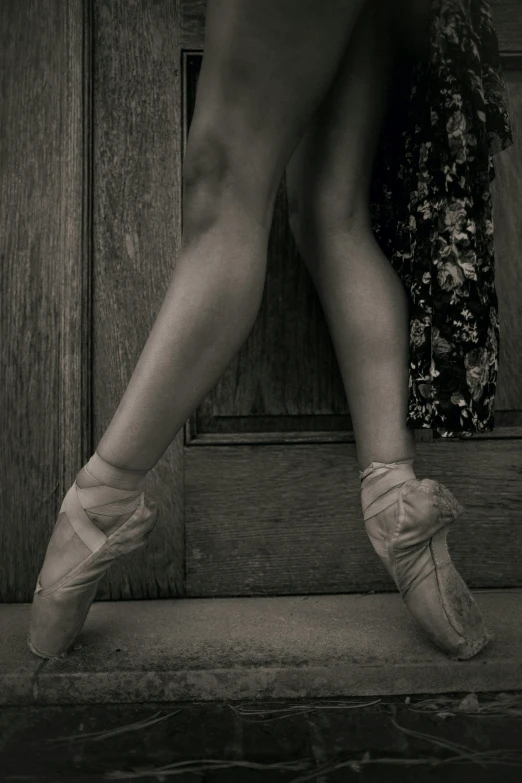 a black and white photo of a ballerina's legs, by Elizabeth Polunin, leaning on door, paul barson, ilustration, a wooden