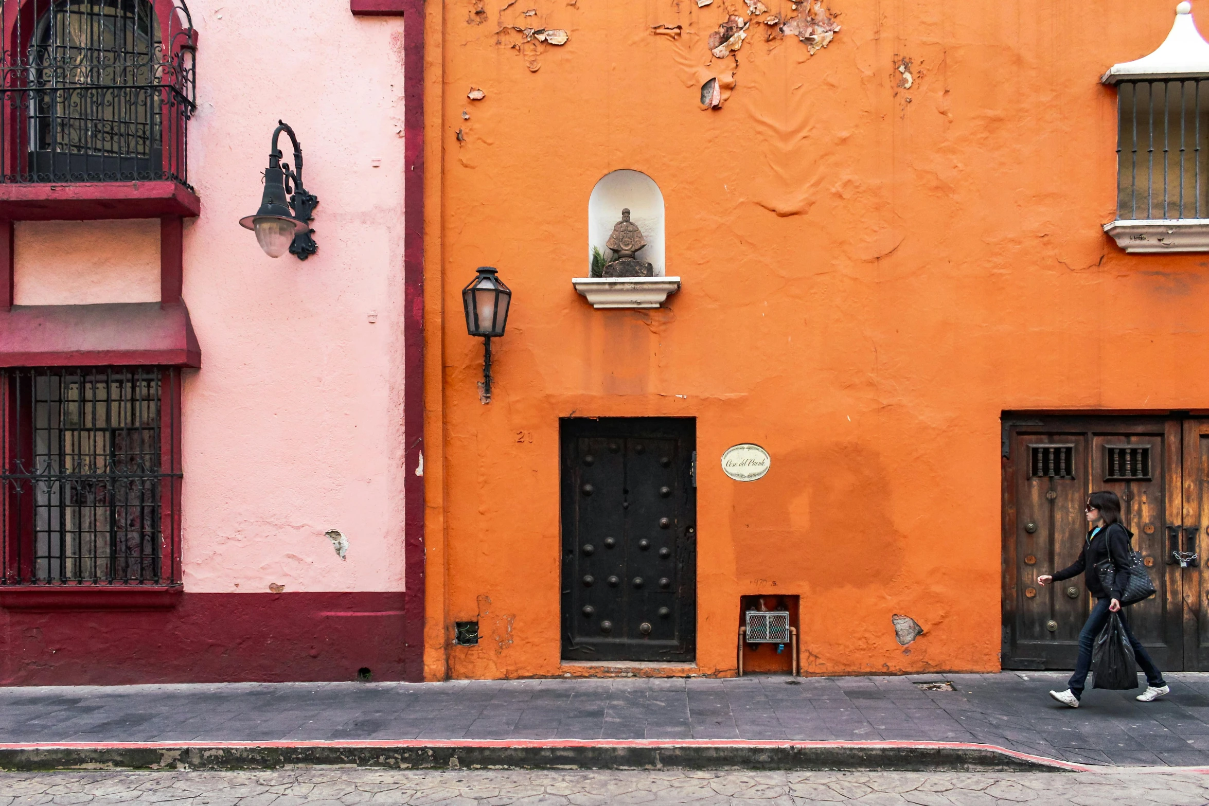 a person on a skateboard in front of a building, a photo, inspired by Agustín Fernández, pexels contest winner, orange color scheme, colonial era street, the walls are pink, downtown mexico